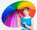 Lovely girl in blue dress under colorful positive rainbow Umbrella on white background. Studio shot, copy space