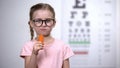 Lovely girl in glasses chewing carrot, vitamin A for good vision, healthcare Royalty Free Stock Photo