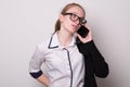 Lovely girl in glasses puts on a jacket. Charming caucasian girl in glasses talking on a cell phone Royalty Free Stock Photo