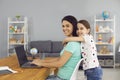 Lovely girl hugging her mom while she working online via laptop at home. Cute child embracing her mother indoors Royalty Free Stock Photo