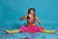 Lovely girl with a multi-colored braids hairstyle and bright make-up, posing in studio with lollipop, air balloons and Royalty Free Stock Photo