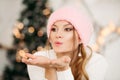 Lovely girl in pink woolen beanie hat making air kiss with hands. Royalty Free Stock Photo