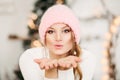 Lovely girl in pink woolen beanie hat making air kiss with hands. Royalty Free Stock Photo