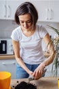 Lovely girl replanting flowers at home  relaxing after working day. Pouring the ground and fertilizer from the packaging  mixing Royalty Free Stock Photo