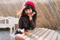 Lovely girl with short hair resting at outdoor cafe in sunny morning and checking mail in social networks. Portrait of Royalty Free Stock Photo