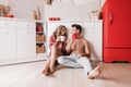 Lovely girl sitting on the floor and having fun with boyfriend. Young couple enjoying coffee or tea in the kitchen Royalty Free Stock Photo