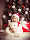 Lovely girl sitting on the floor near the Christmas tree with a bear, studio shot, toning in vintage style. Royalty Free Stock Photo