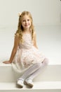 Lovely girl sitting on white staircase. Studio portrait.