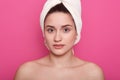 Lovely girl wearing white towel on head, posing with bared shoulders isolated over pink studio background, attractive lady looking Royalty Free Stock Photo