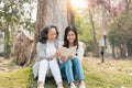 Lovely granddaughter and grandmother sitting under the tree in the green park, read a book together Royalty Free Stock Photo