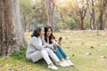 Lovely granddaughter and grandmother sitting under the tree in the green park together, watching Social news on Royalty Free Stock Photo