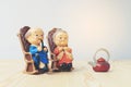 Lovely grandparent doll siting old sofa classic chair together on wooden table with background.