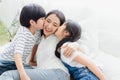 Lovely happy Asian family at cozy home. Son and daughter kiss mother with enjoy ,relax and playful together in bedroom. Happiness