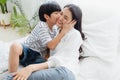 Lovely happy Asian family at cozy home. Son kiss smiling mother with enjoy ,relax and playful together in bedroom. Happiness