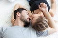 Lovely happy couple in love, smile, and kiss each other on their bed in the bedroom Royalty Free Stock Photo