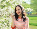 Lovely happy smiling young woman in spring blooming garden with white flowers on the trees in park Royalty Free Stock Photo