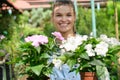 Lovely happy young woman gardener choosing flower pot with anthuriums in garden center Royalty Free Stock Photo