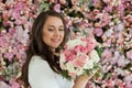 Lovely healthy woman smiling and holding colorful pink color flower bouquet on floral spring or summer background, studio fashion Royalty Free Stock Photo