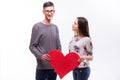 Lovely hipster couple with a red heart in hands. Man look at camera, girl look at man. Royalty Free Stock Photo