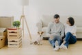 Lovely husband and wife sit in new apartment with laptop computer, discuss home repair project, pose in living room with sofa, Royalty Free Stock Photo