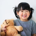 Lovely and innocent asian kid with teddy smiled happily