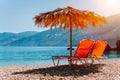 Lovely isolated beach and sunbeds under straw umbrella at warm sunset light