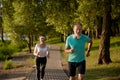 Lovely joyful retirees couple jogging outside in city park in morning