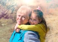 Lovely kid girl hangs on grandmother neck  hugs her from behind piggybacking and laughing together. Hugs and joy with grandma Royalty Free Stock Photo