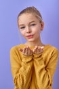 lovely kid girl 12-13 years old in yellow shirt sending air kiss isolated on purple Royalty Free Stock Photo