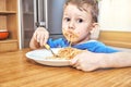 Lovely kid with large eyes eats sloppy delicious pasta