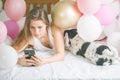 Lovely lady in pajama making selfie in her bedroom using phone and hanging out with her dog. Indoor portrait  girl with baloons in Royalty Free Stock Photo