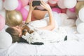 Lovely lady in pajama making selfie in her bedroom using phone and hanging out with her dog. Indoor portrait  girl with baloons in Royalty Free Stock Photo