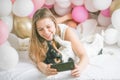 Lovely lady in pajama making selfie in her bedroom using phone and hug her dog. Indoor portrait  girl with baloons in morning. Royalty Free Stock Photo