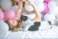 Lovely lady in pajama making selfie in her bedroom using phone and hug her dog. Indoor portrait  girl with baloons in morning. Royalty Free Stock Photo