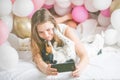 Lovely lady in pajama making selfie in her bedroom using phone and kiss her dog. Indoor portrait  girl with baloons in morning. Royalty Free Stock Photo