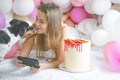 Lovely lady in pajama making selfie in her bedroom using phone and play with her dog. Indoor portrait girl with baloons in