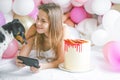Lovely lady in pajama making selfie in her bedroom using phone and play with her dog. Indoor portrait  girl with baloons in Royalty Free Stock Photo