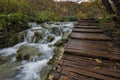 Lovely landscape with beautiful waterfall, wooden path and autumn forest