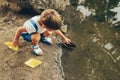 Lovely little boy launches paper ship on the lake in the park. Adorable kid boy playing with a boat. Child sailing a toy boat by Royalty Free Stock Photo