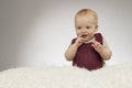 Lovely little boy smiling, sitting on the white blanket, studio shot, isolated on grey background, funny baby portrait Royalty Free Stock Photo