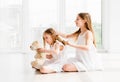 Lovely little girl brushing hair of younger sister