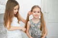 Little girl makes ponytails of her younger sister