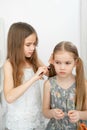 Little girl makes ponytails of her younger sister