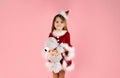 Lovely little girl in Christmas dress isolated on pink background holds her teddy bear in her arms and smiles Royalty Free Stock Photo