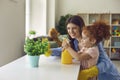 Lovely little girl helping her mother water houseplant at home, copy space text.