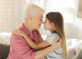 Lovely little girl and her grandma touching noses and embracing at home Royalty Free Stock Photo