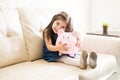 Lovely little girl with her piggy bank at home Royalty Free Stock Photo