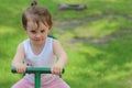 Lovely little girl kindergartner rides on a swing on a playground against a background of green grass