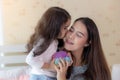 Lovely little girl kissing her mom at cheek for giving love to her beautiful mother. Asian mother get happiness when her cute Royalty Free Stock Photo