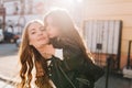Lovely little girl kissing mother in cheek and gently touching her face enjoying sunshine in morning. Family portrait of Royalty Free Stock Photo